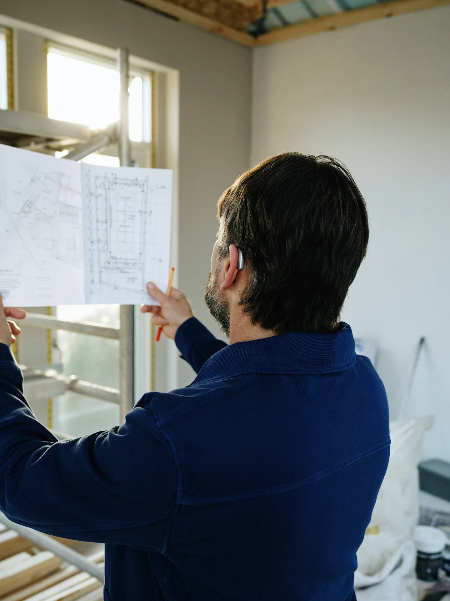Builder reviewing a plan set on an active job site